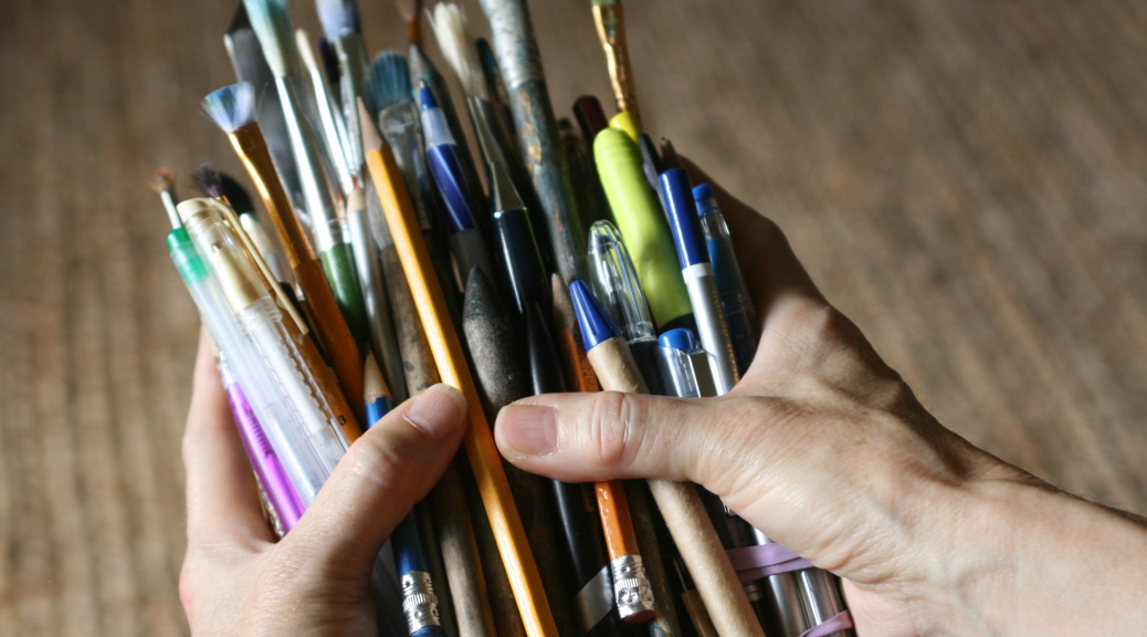 Dorene's hands filled with pencils, pens, paint brushes and markers